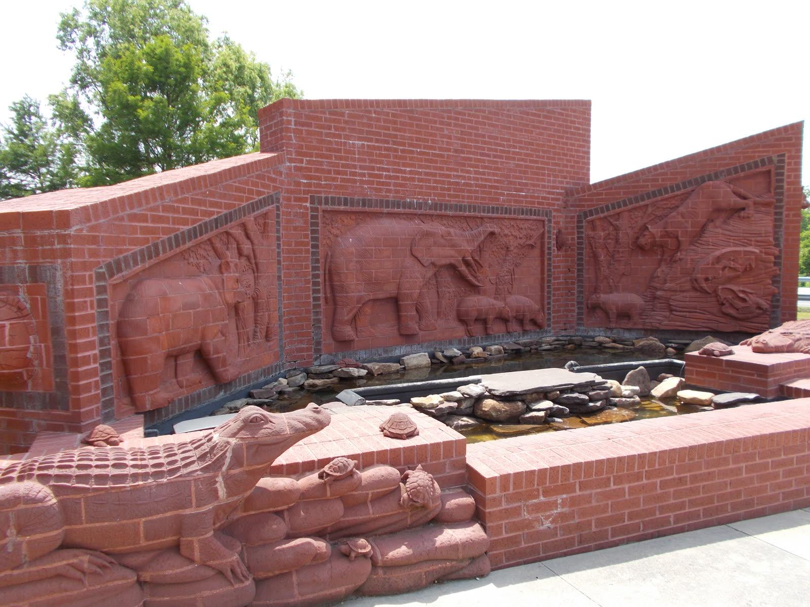 Red brick relief sculptures of a large elephant, bears and an alligator in a pool at the entrance to the Gray Fossil Site museum