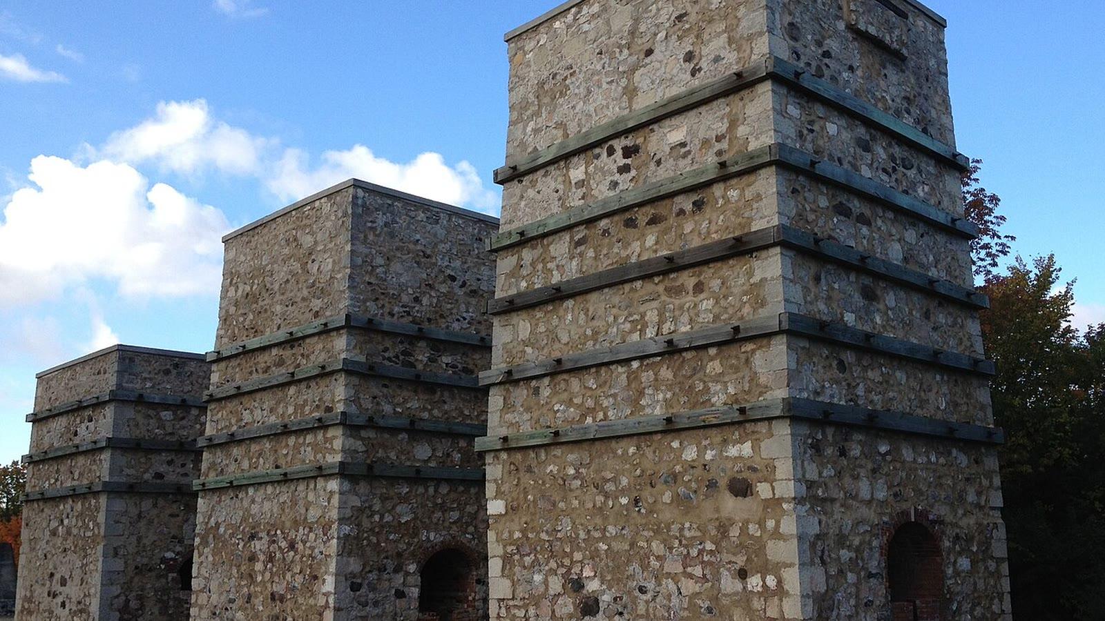 Three restored stone lime kilns standing in a row under a blue sky at Lime Kiln Park, Grafton, Wisconsin