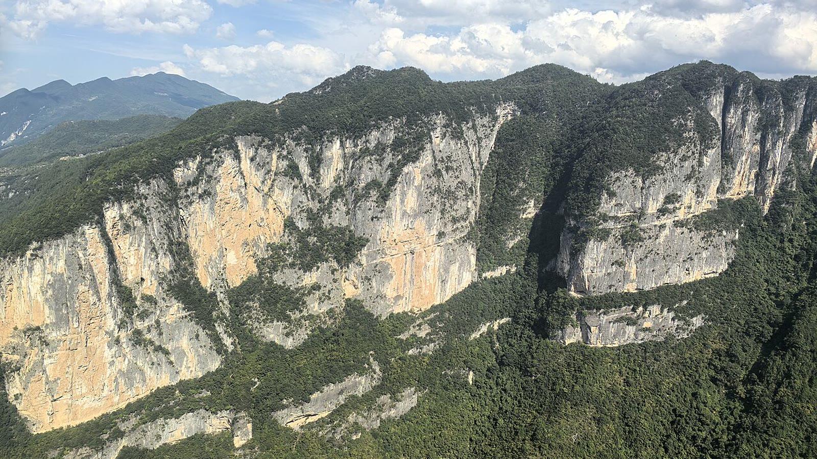 Karst cliffs and forested slopes at Longgang in Yunyang County, inside the same geopark as the dinosaur fossil wall