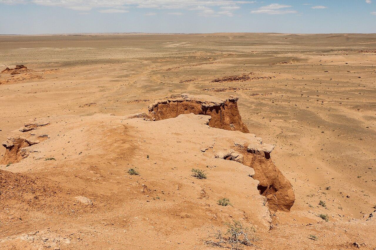 Orange sandstone cliffs glowing above the desert floor at Bayanzag, the Flaming Cliffs, Gobi Desert.