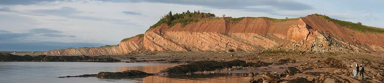 Layered coal-bearing cliffs rising above the cobbled beach at the Joggins Fossil Cliffs, Nova Scotia.