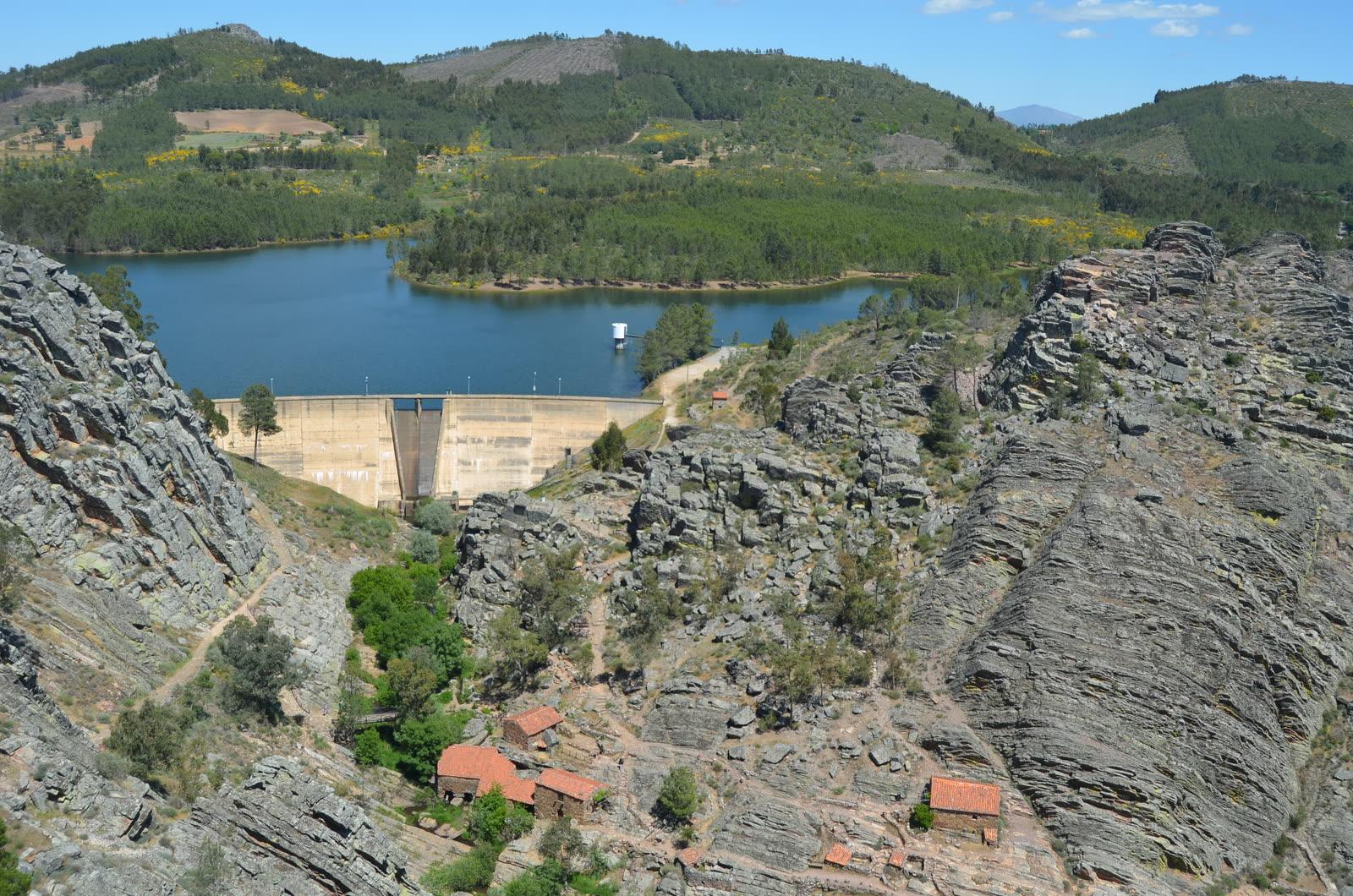 Gorge viewed from above with a concrete dam and reservoir behind and steeply tilted grey quartzite beds on the right-hand slope.