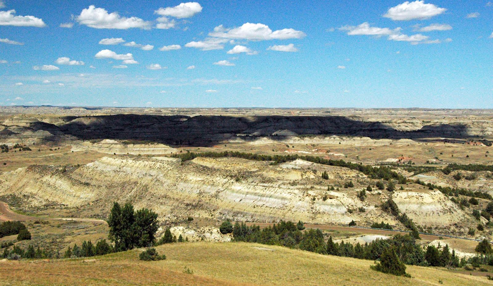 Wide view over the South Unit badlands of Theodore Roosevelt National Park from Buck Hill, with pale Sentinel Butte slopes above green valleys