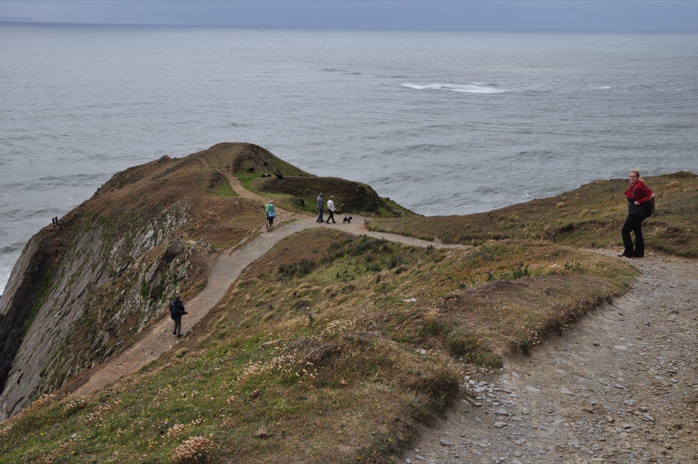 A coastal path running out along the grassy headland of Baggy Point, north Devon.