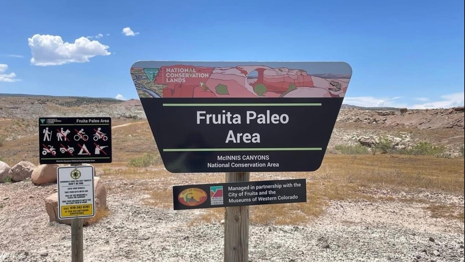 Fruita Paleo Area entrance sign for the McInnis Canyons National Conservation Area, with the pale Morrison badlands behind it.