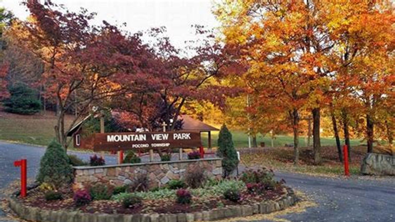 Stone-base park entry sign reading 'Mountain View Park, Pocono Township' framed by autumn maples in red and orange.