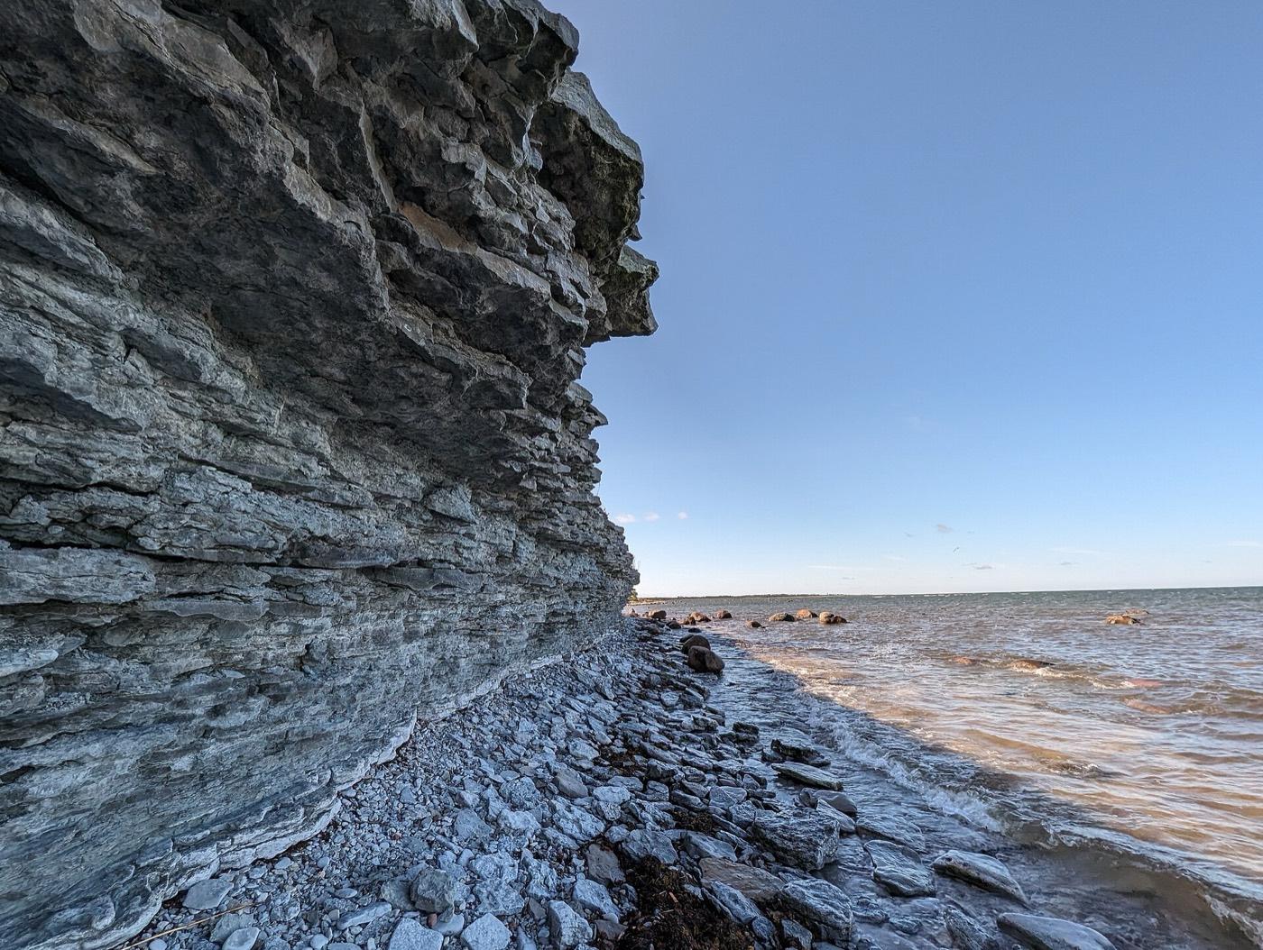 The layered limestone face of Ohesaare cliff on Saaremaa, shingle beach at its foot