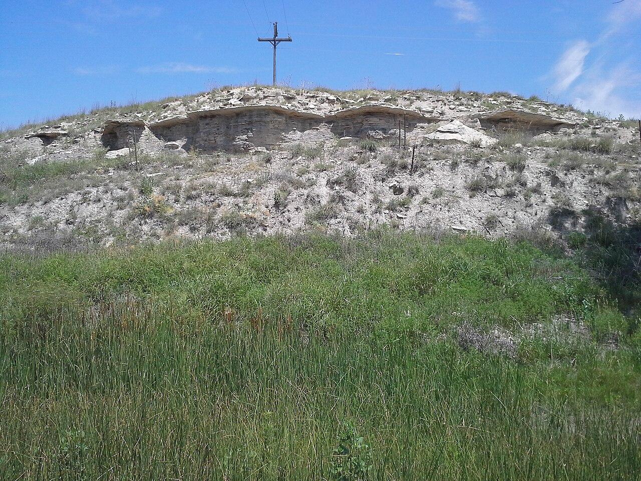 A pale chalk butte of the Pfeifer Shale rising above open grassland in southern Ellis County, Kansas