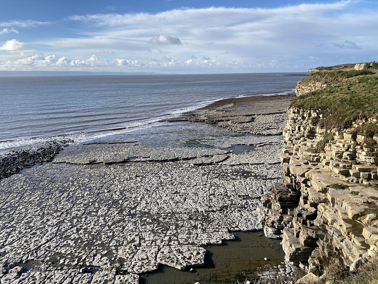 A wave-cut limestone pavement running out from layered cliffs on the Glamorgan Heritage Coast
