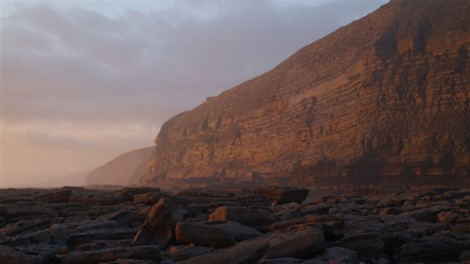 Sunset light on layered cliffs and rocky tidal platform along the Heritage Coast at Southerndown, Glamorgan.