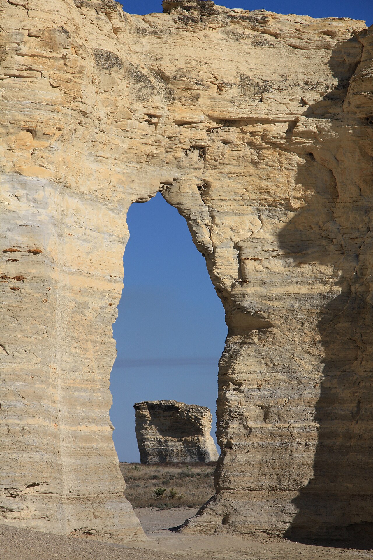 Tall pale chalk spires rising from flat shortgrass prairie under an open sky at Monument Rocks, Gove County, Kansas.